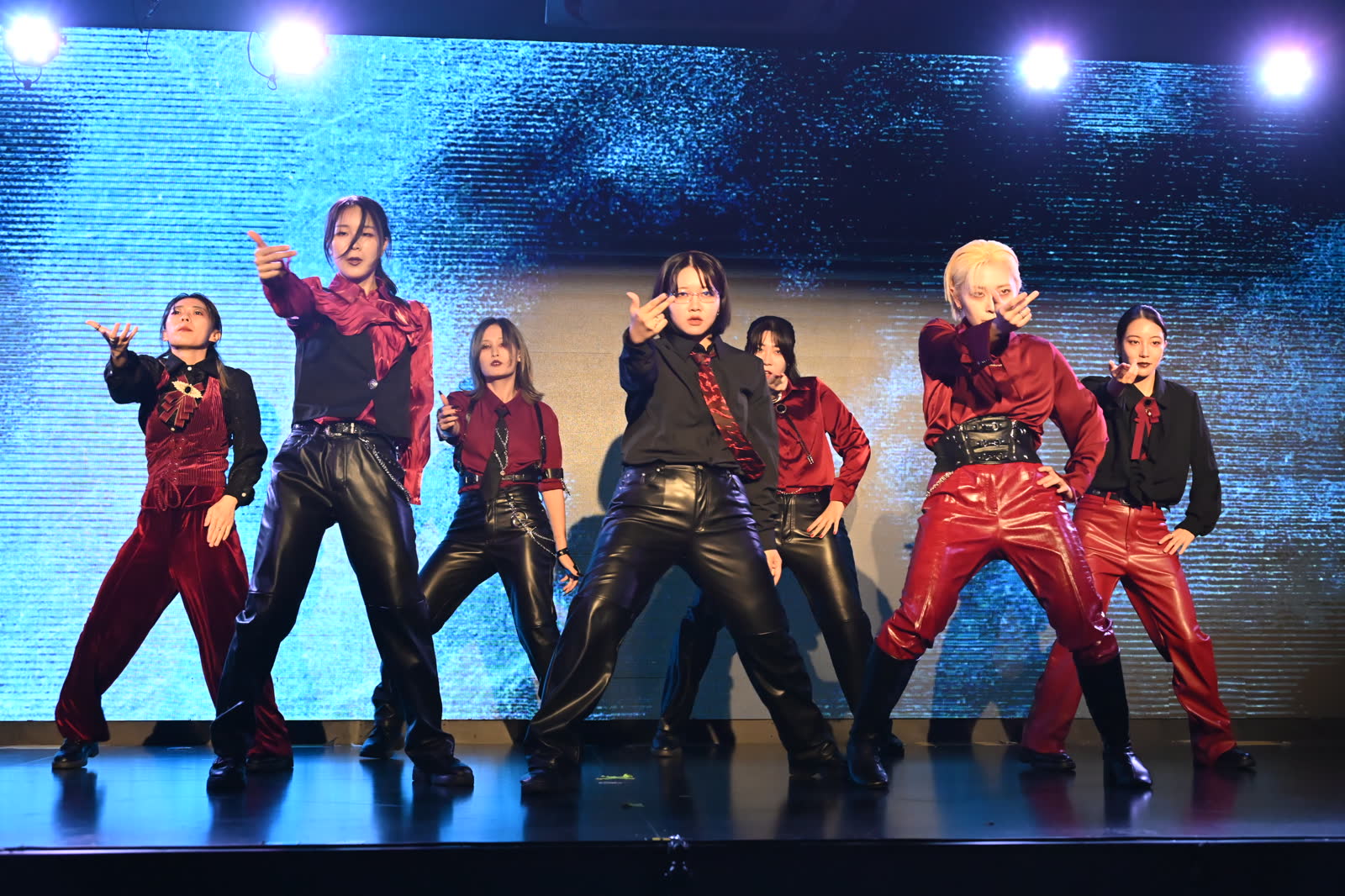 赤と黒の衣装を着たダンスチームが正面を向いて踊る様子
