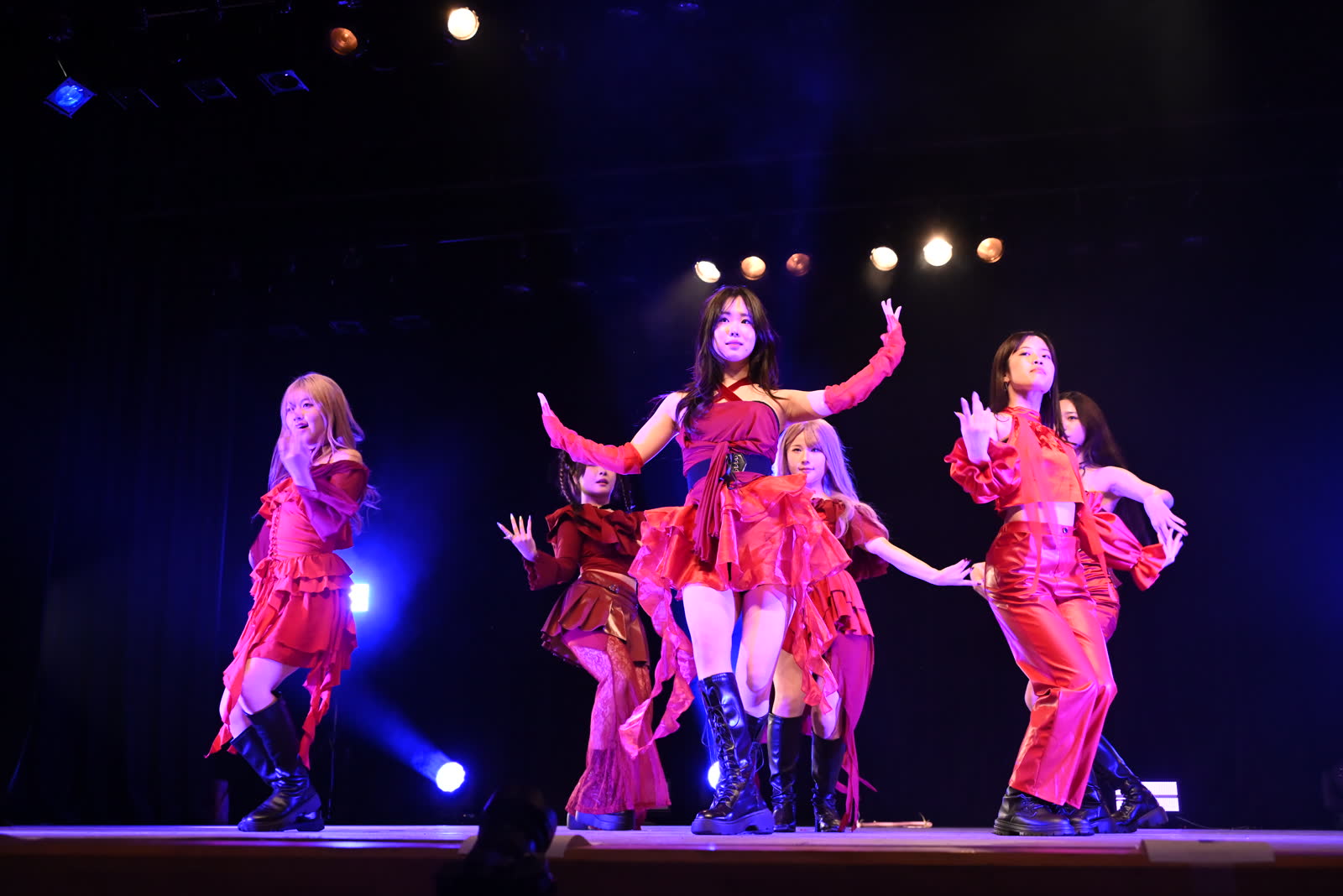 赤い衣装のダンスチームがライブステージでポーズを決める様子