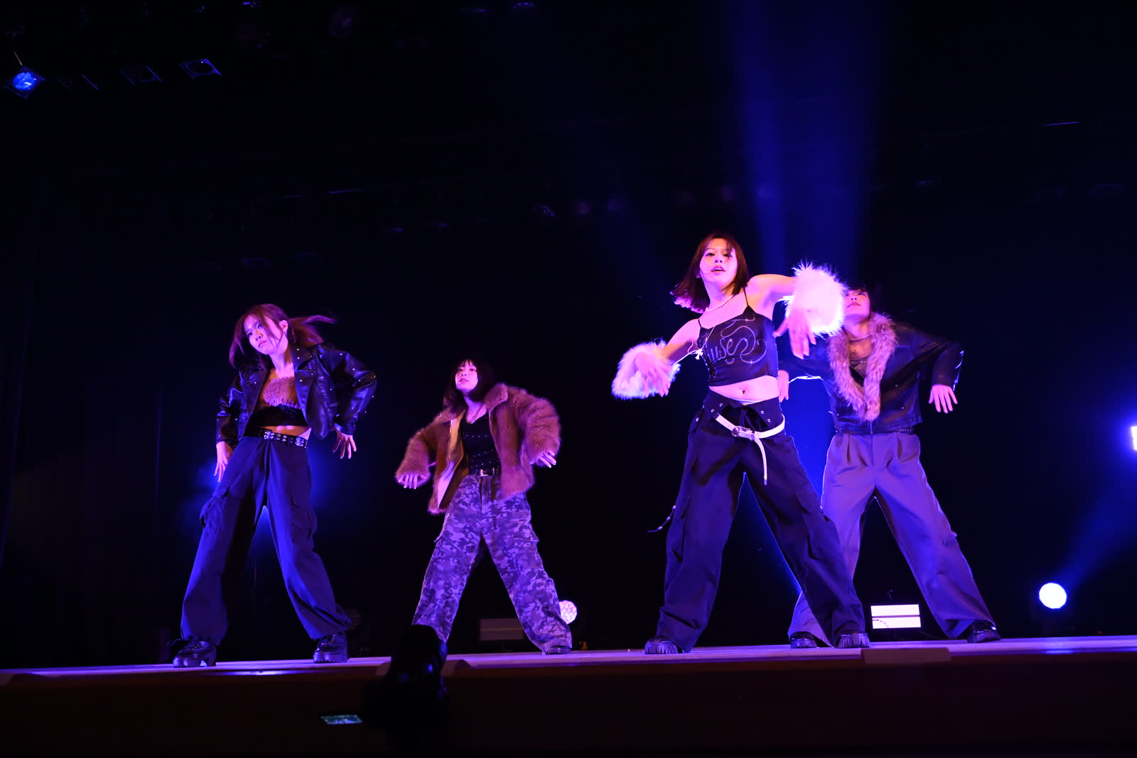 青い照明のライブステージで4人のダンサーが踊る様子